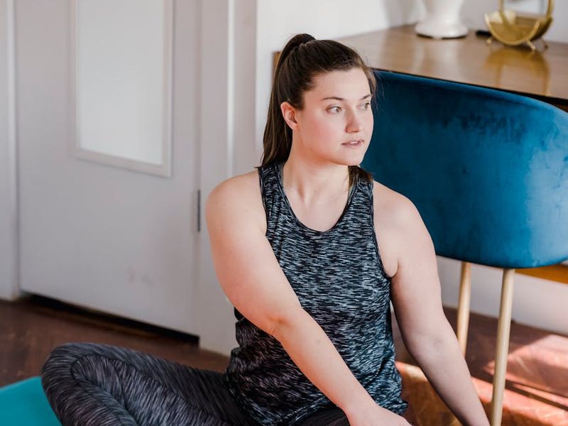 Woman performing a focused yoga stretch in a minimalist room.